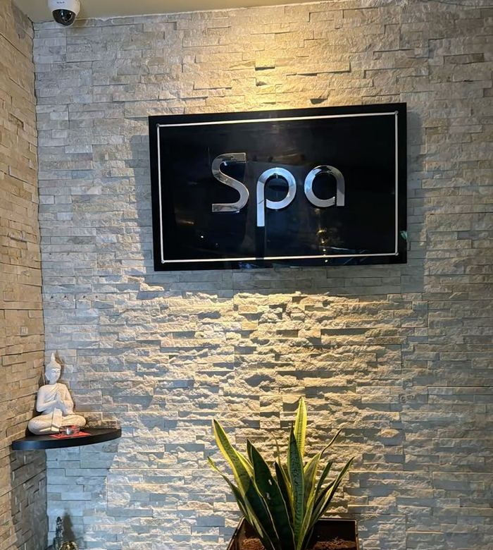Spa reception wall with a lit sign, stone cladding and a potted plant