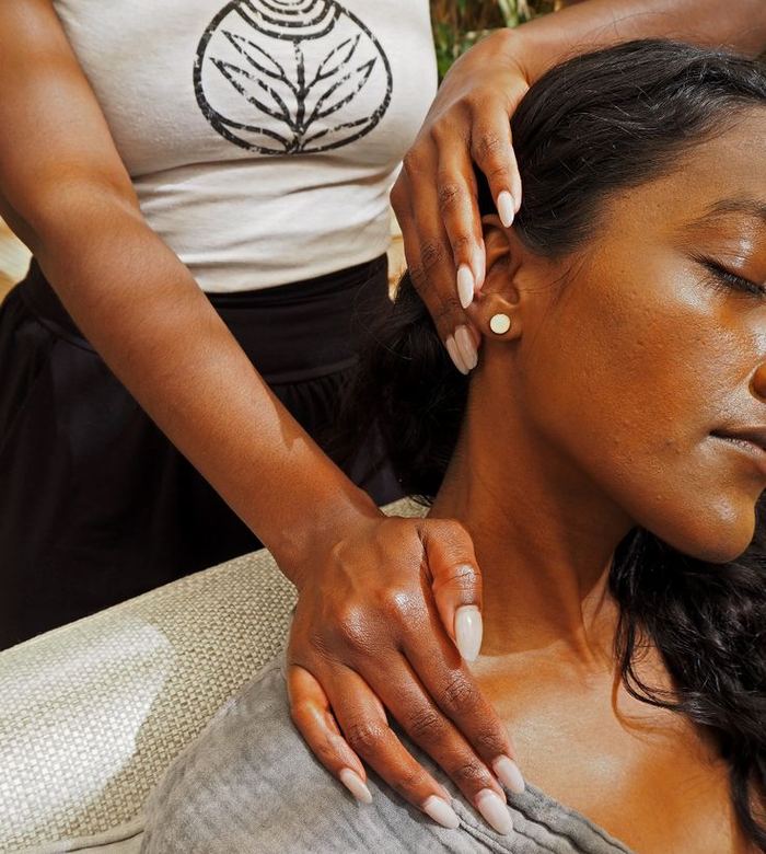 Therapist massaging a seated client's neck and shoulders