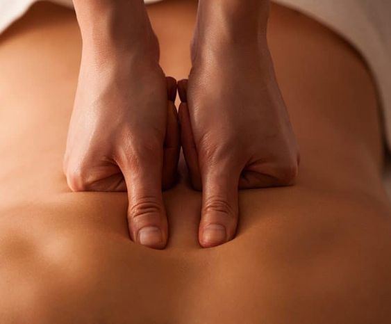 Therapist using both thumbs to apply firm pressure along a client's spine