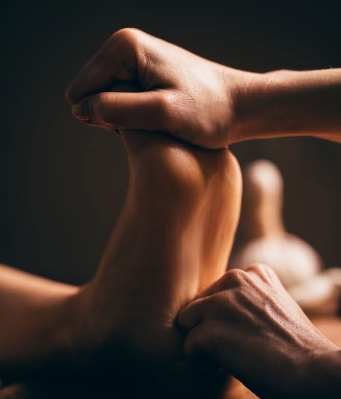 Therapist applying reflexology pressure to the sole of a client's foot