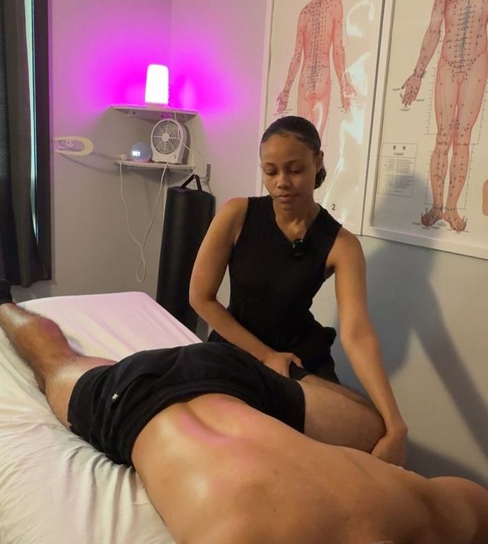 Therapist working on a client's hamstring and glute during a sports massage