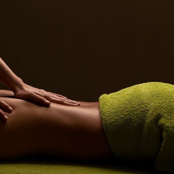 Relaxed Swedish massage strokes along a client's back, draped with a towel